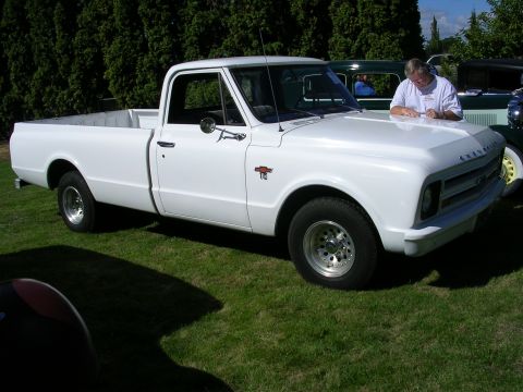 1996 Ford Probe - A man writes on the hood of a white 1967 Chevrolet C10 pickup truck at an outdoor event.