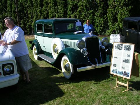 1996 Ford Probe - A vintage green and white sedan is displayed at a car show, with a display board of historical photos nearby.