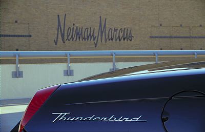 2002 Ford Thunderbird - A dark blue 2002 Ford Thunderbird is seen from the rear, with the 'Neiman Marcus' logo visible on a building in the background.