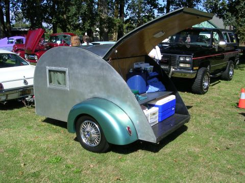 1996 Ford Probe - A teardrop trailer and a GMC SUV are parked on a grassy field, with other vehicles in the background.