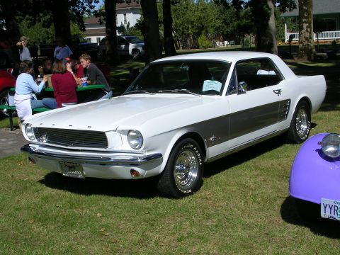 1996 Ford Probe - A classic white Ford Mustang is displayed at an outdoor event, with attendees gathered nearby.