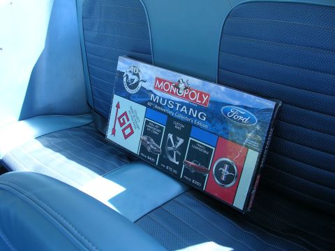 1996 Ford Probe - A Monopoly Mustang 40th Anniversary Collector's Edition box rests on the blue interior seats of a vehicle.