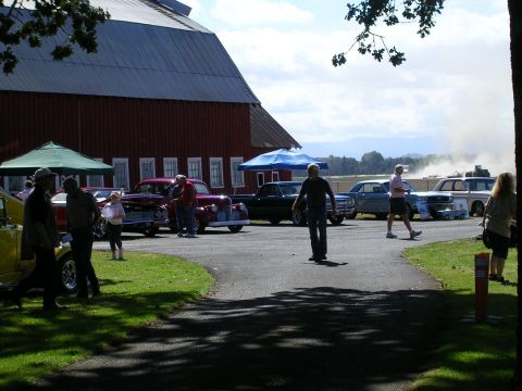 1996 Ford Probe - People gather at an outdoor car show event with a large red barn in the background.