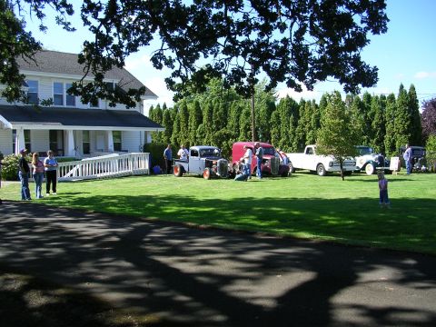 1996 Ford Probe - A gathering of classic vehicles is displayed on a grassy lawn outside a residence.