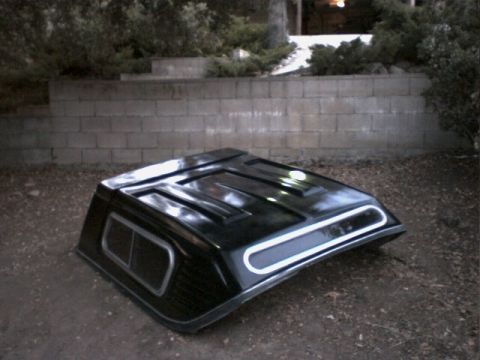 1972 Ford Ranchero - A black truck bed cap sits on the ground in front of a cinder block wall.