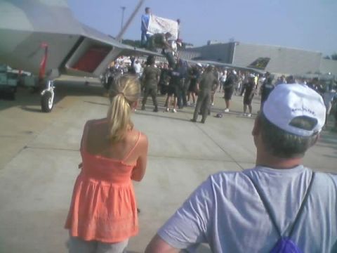 1989 Ford Bronco - An air show scene with a fighter jet and a crowd of onlookers, viewed from behind two people in the foreground.