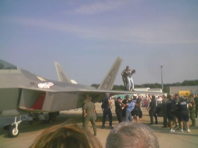 Fighter jet with people on wing, crowd gathered