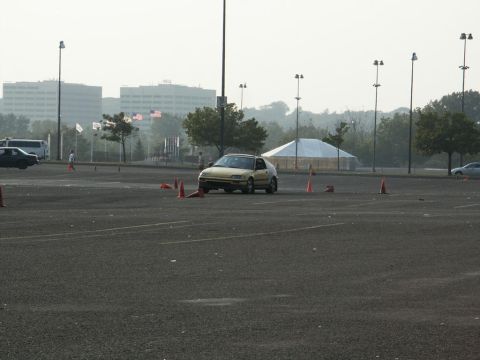 2001 Mercury Grand Marquis - A yellow hatchback navigates a course marked by traffic cones in an empty parking lot.