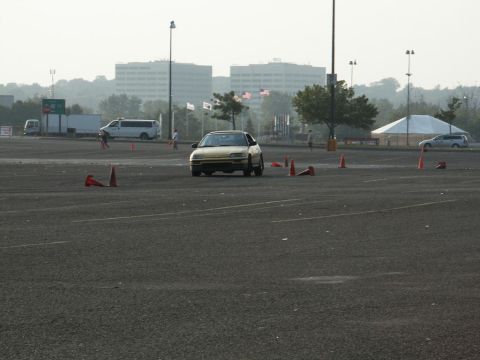 2001 Mercury Grand Marquis - A yellow sedan navigates a course marked by orange cones in a large paved area.