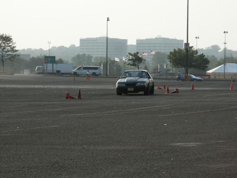 2001 Mercury Grand Marquis - A black coupe with an aftermarket hood navigates a cone course on a hazy day.