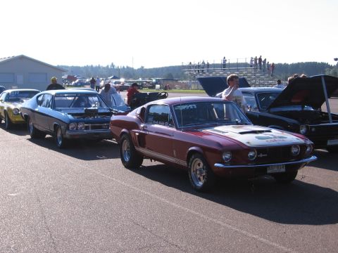1989 Ford Mustang - Several classic muscle cars are lined up on a track, possibly for a race or car show.