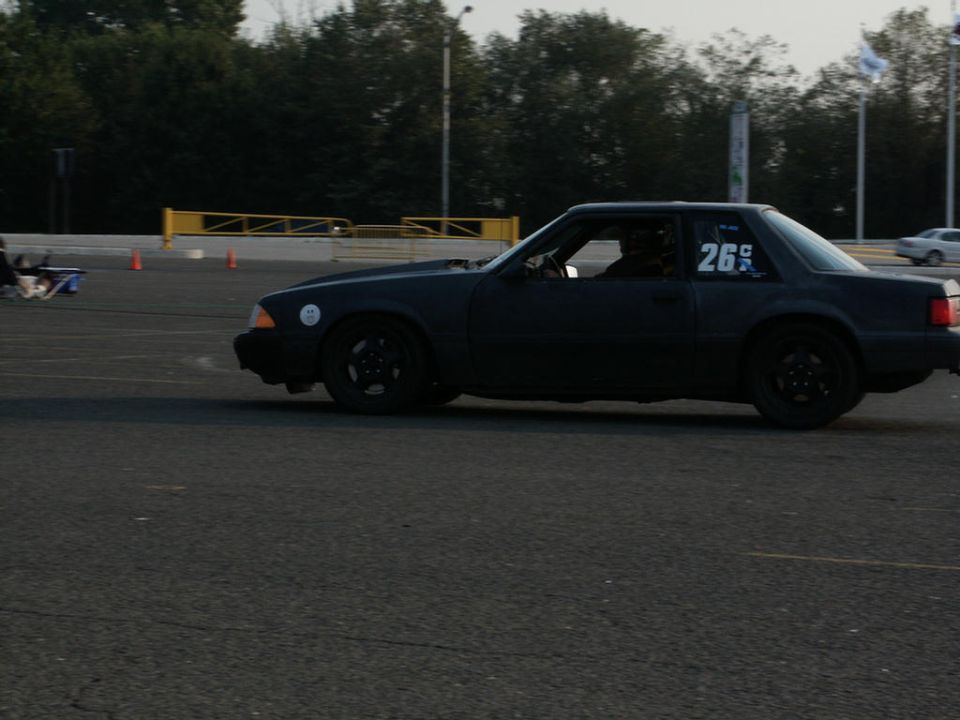 Side view of a black coupe with number 26 on the door, on a race track