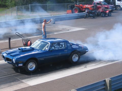 1989 Ford Mustang - Blue muscle car performing a burnout at a drag strip.