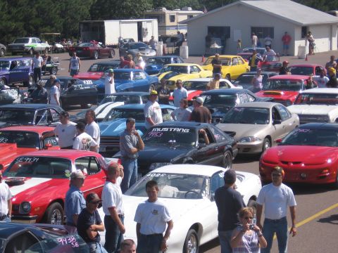1989 Ford Mustang - A black 1989 Ford Mustang is parked among other vehicles at what appears to be a car show or race event.