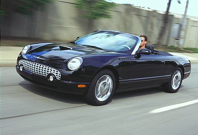 2002 Ford Thunderbird - A black 2002 Ford Thunderbird convertible is shown driving on a highway.