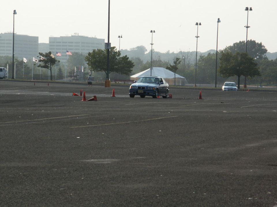 Blue sedan navigating a cone course with another car in the background