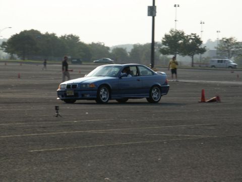 2001 Mercury Grand Marquis - A blue BMW coupe navigates a course marked by traffic cones on a paved lot.