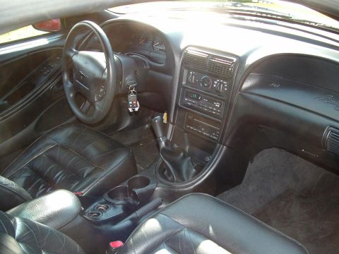 1998 Ford Mustang - The interior of a 1998 Ford Mustang features black leather seats and a dashboard with a radio and climate controls.