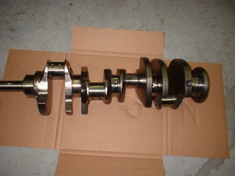 1969 Ford Mustang - A metal crankshaft is laid out on a piece of cardboard on a concrete floor.