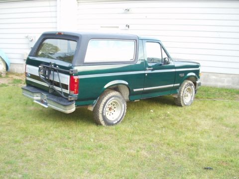 1993 Ford Bronco - This green Ford Bronco is parked outside a building on a grassy area.