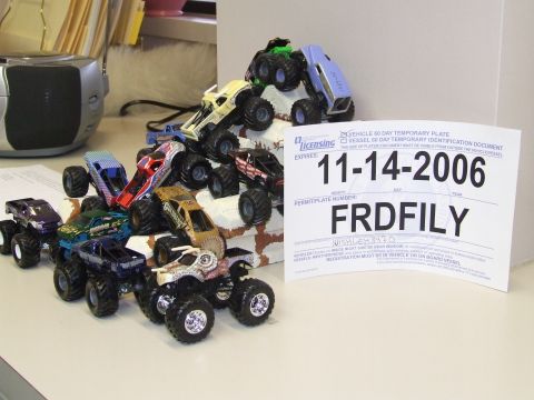 1979 Ford Bronco - A group of toy monster trucks are displayed with a temporary vehicle registration document.