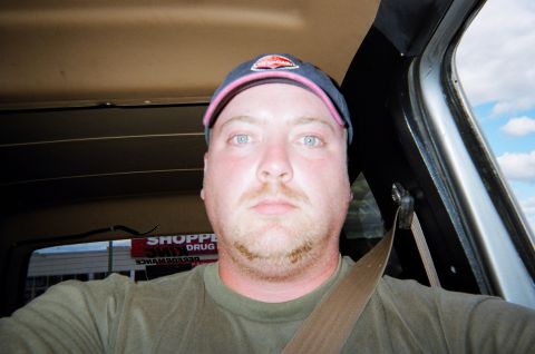 1984 Ford Bronco - Man in a vehicle interior, with a seatbelt fastened and a baseball cap on.