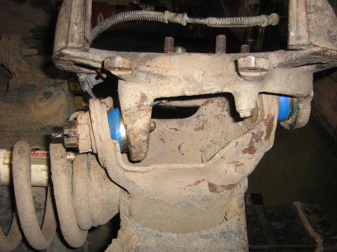 1995 Ford Bronco - This image shows a close-up of a vehicle's suspension system, focusing on a ball joint area with visible blue bushings.