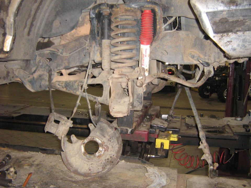 Front suspension components with red shock absorber and brake rotor removed