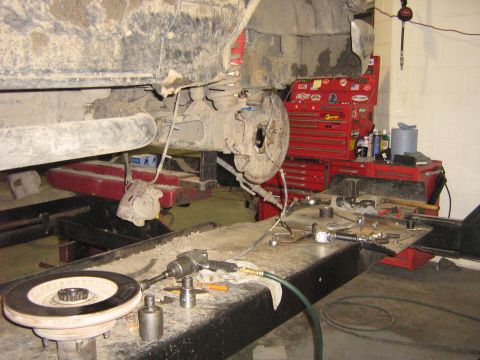 1995 Ford Bronco - The rear axle of a vehicle is disassembled on a lift, with tools and a toolbox ready for repair.