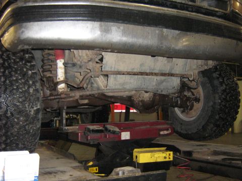 1995 Ford Bronco - The underside of a vehicle is examined, revealing suspension components and a differential.