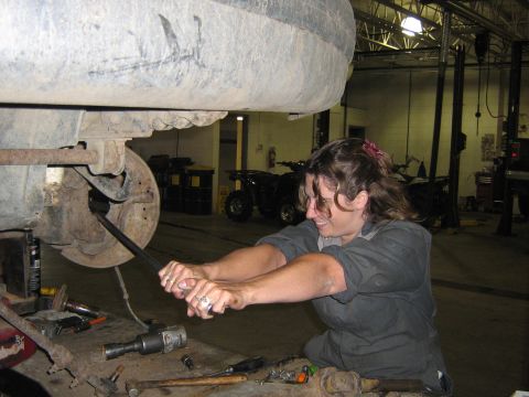 1995 Ford Bronco - Mechanic works on suspension components in a workshop setting.