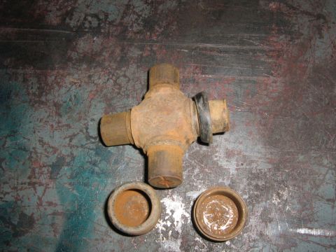 1995 Ford Bronco - A rusty universal joint and its associated caps are shown on a textured metal surface.