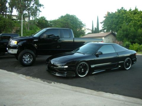 1994 Ford Probe - A black 1994 Ford Probe is parked next to a lifted black Ford F-150 truck.