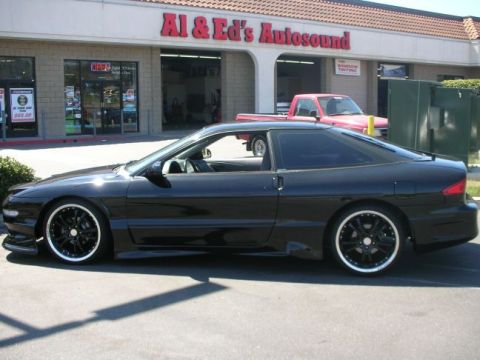 1994 Ford Probe - A black 1994 Ford Probe is parked outside Al & Ed's Autosound, with a red pickup truck visible in the background.