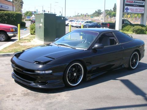 1994 Ford Probe - A black 1994 Ford Probe is parked in a lot, showing its sporty design and custom wheels.