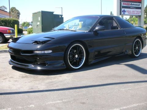 1994 Ford Probe - This black 1994 Ford Probe features pop-up headlights and aftermarket wheels, seen from a three-quarter front angle.