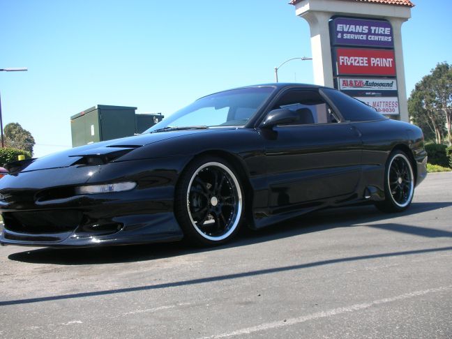 Black 1994 Ford Probe parked outside a strip mall