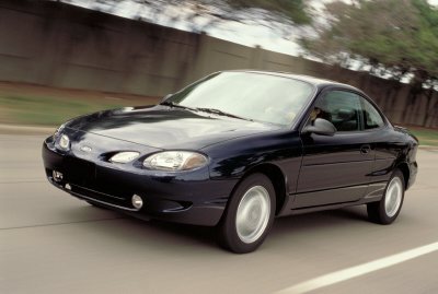 2002 Ford Escort - A dark blue 2002 Ford Escort coupe is captured in motion on a highway, its front three-quarter profile.
