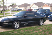 1997 Ford Probe - A black Ford Probe GTS is parked in a suburban driveway with other vehicles visible.