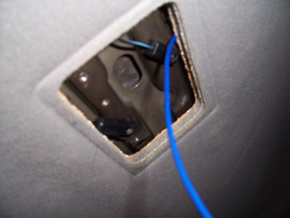 Interior ceiling light fixture opening with exposed wiring and a blue cable. The surrounding material is gray fabric