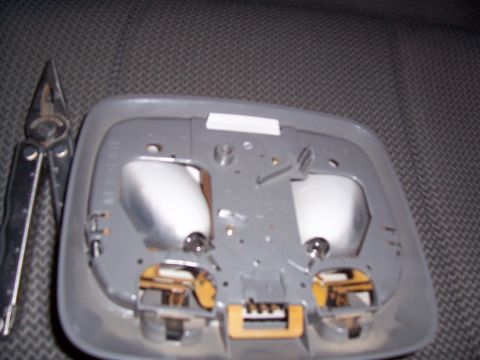2003 Ford Ranger - A close-up view of a disassembled interior light assembly, with a pair of pliers resting to the side.