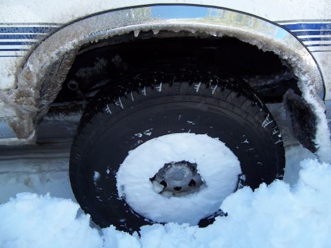 1996 Ford Bronco - Vehicle's wheel well and tire are encased in ice and snow, suggesting harsh winter conditions.