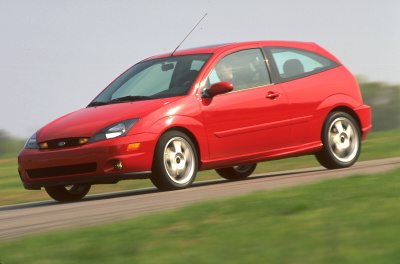 2002 Ford Focus - This red 2002 Ford Focus SVT hatchback is captured in motion on a paved road, its sporty design.