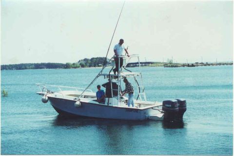 1978 Ford F-250 - A fishing boat with several people on deck sails on the water under a bright sky.