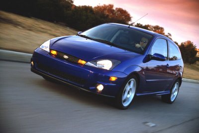 2002 Ford Focus - A blue 2002 Ford Focus SVT is captured in motion on a road during sunset.