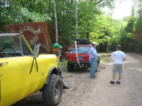 1997 Dodge 1500 - Two vehicles are parked on a dirt road in a wooded area, with people interacting between them.