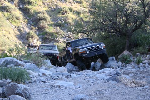 1966 Ford Bronco - Two trucks are off-roading on a rocky, mountainous trail.