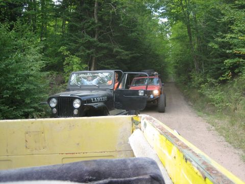1997 Dodge 1500 - Two off-road vehicles travel down a wooded dirt path, one in front of the other.