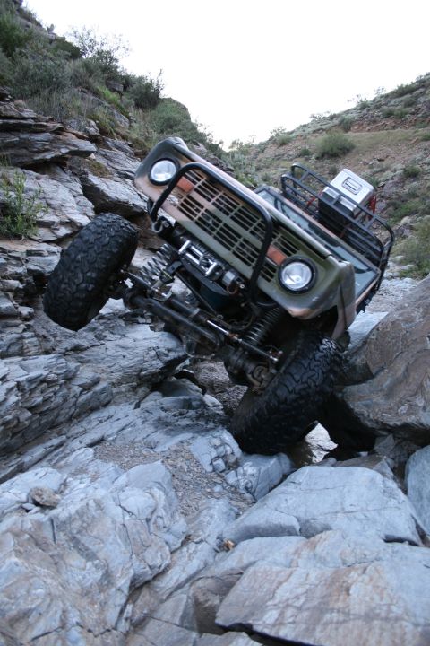 1966 Ford Bronco - A 1966 Ford Bronco navigates a rocky, off-road trail with its front end angled upwards.