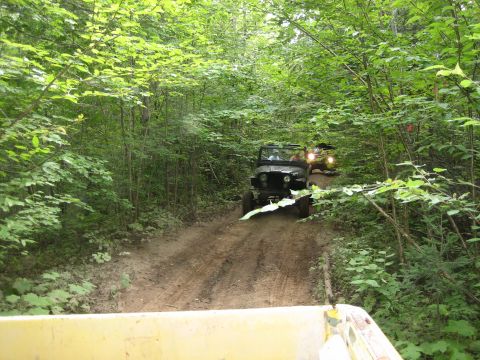 1997 Dodge 1500 - Two off-road vehicles navigate a wooded trail, kicking up dust on the path ahead.